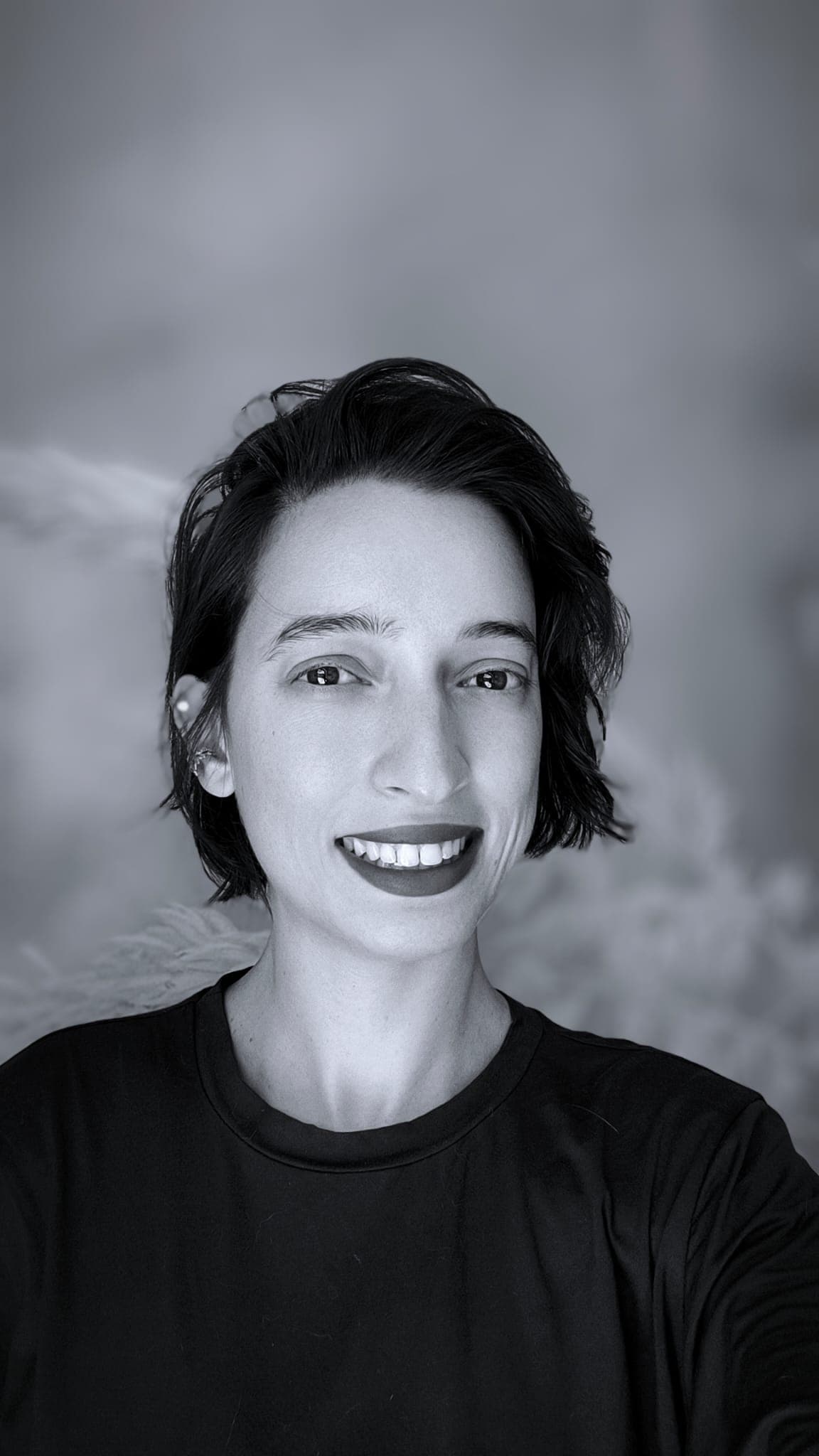 Portrait of Thamiris smiling against a neutral background.